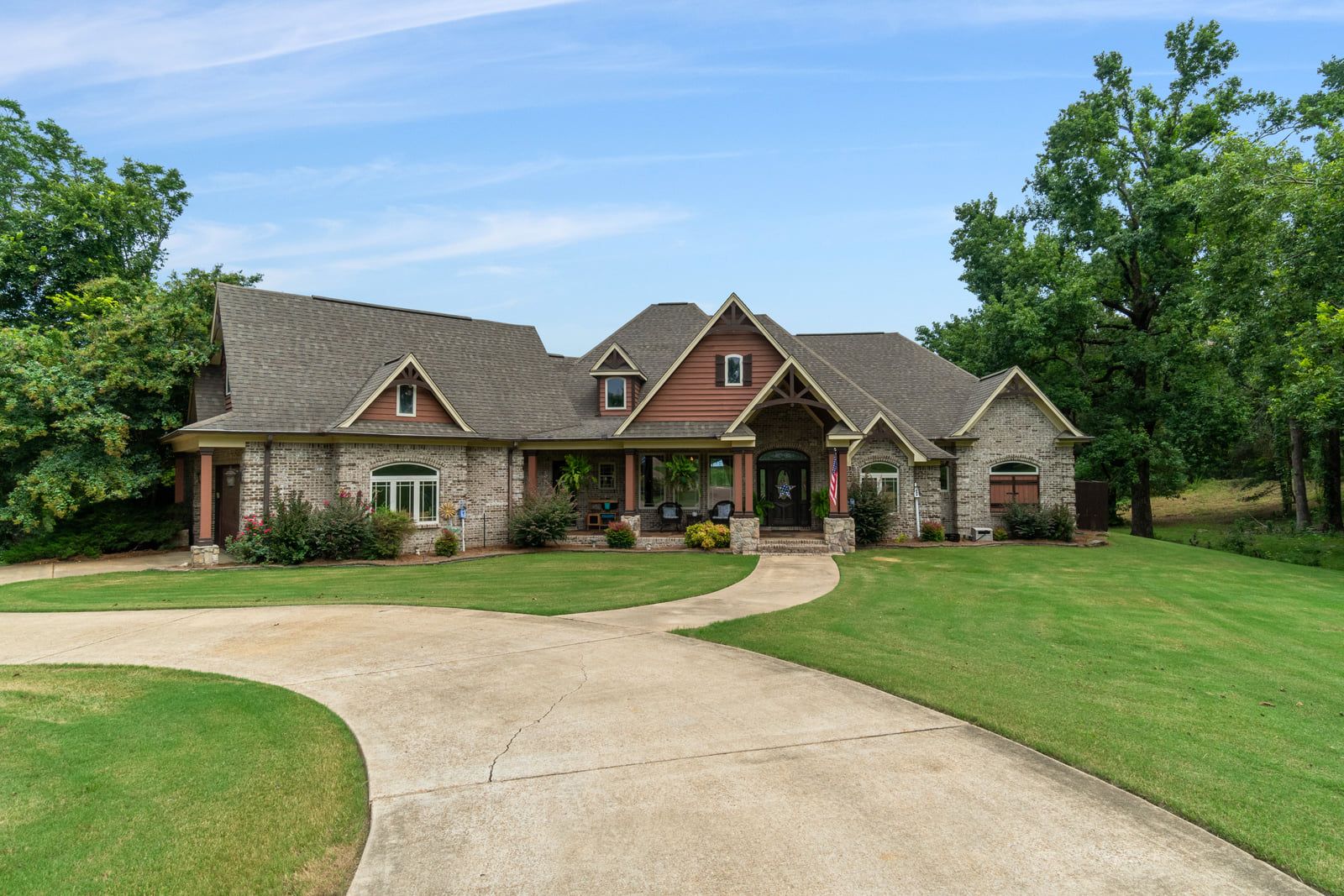 Front elevation with the drive curving in past mature oaks.